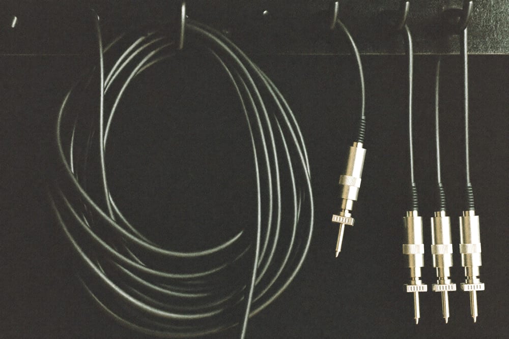 A neat loom of black audio cables coiled on a hook beside plain connectors.